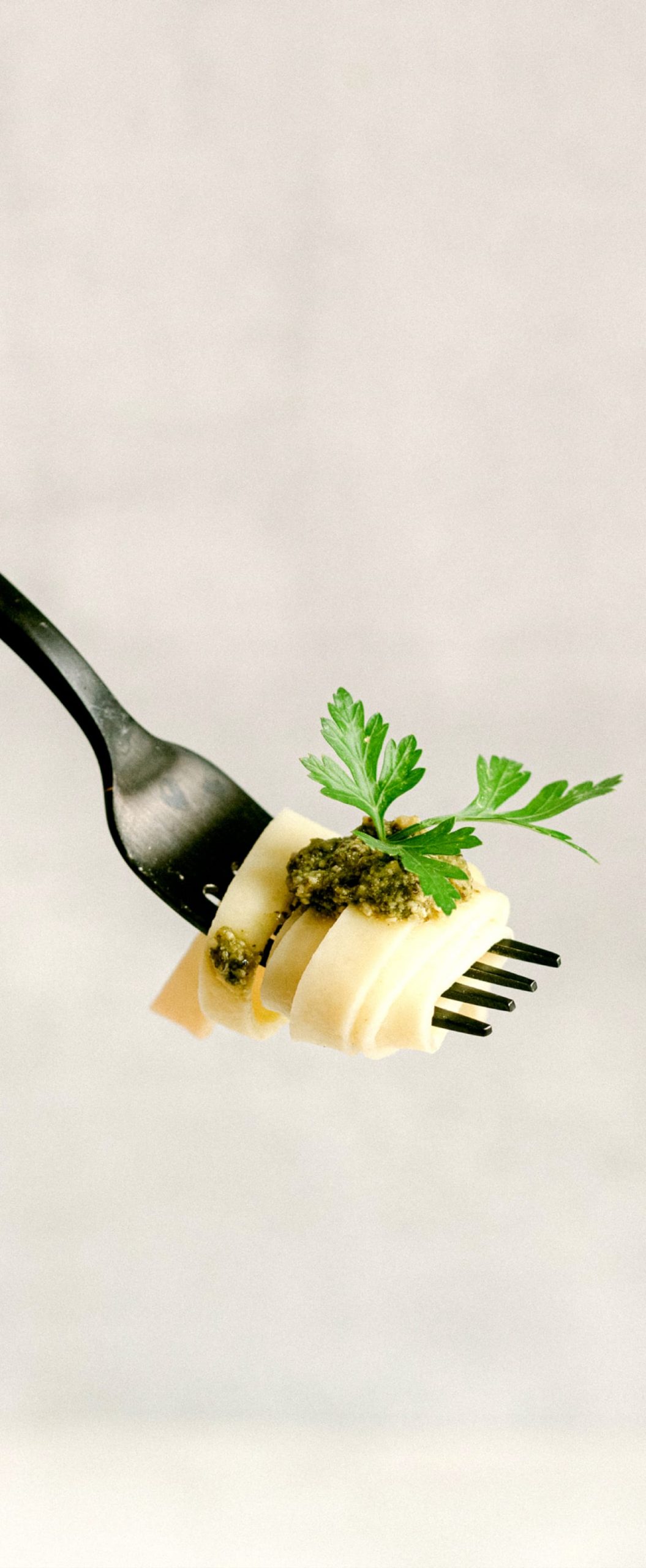 Fork twirled with spaghetti, topped with spinach and garnished with a green leaf