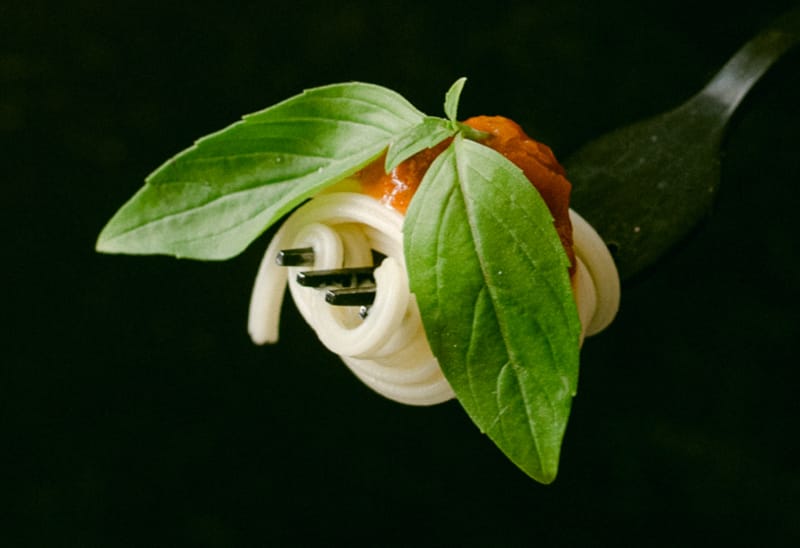 Fork twirled with spaghetti, topped with mince and garnished with a green leaf