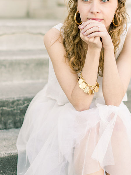 Woman in  white dress, appearing thoughtful.